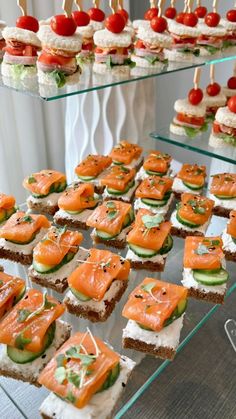 there are many small sandwiches on the glass trays with toothpicks in them