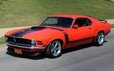 an orange mustang with black stripes parked on the street