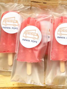 three pops are in plastic bags on a table with stickers that say papaya pops