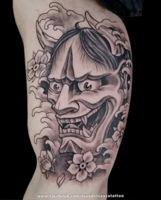 a tattoo with an image of a demon and flowers on the side of his leg