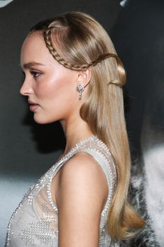 a woman with long blonde hair wearing a braided ponytail and diamond earrings on her head