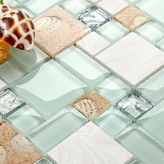 a vase filled with flowers sitting on top of a glass tile floor covered in sea shells