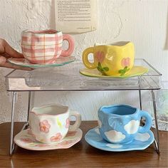 three coffee cups and saucers are sitting on a glass shelf next to each other