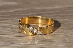 a gold ring with two diamonds on it sitting on top of a wooden table next to a pair of scissors