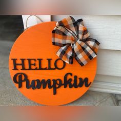 a wooden sign that says hello pumpkin with a bow hanging on the side of it