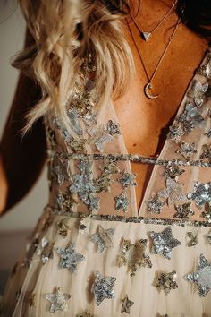 the back of a woman's dress with silver stars on it and a gold necklace