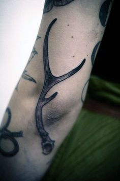 a man's arm with scissors and deer antlers on it