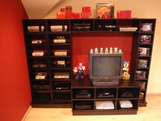 a television sitting on top of a wooden shelf in front of a wall filled with video games