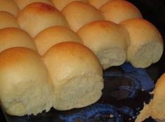 rolls are being cooked in the oven on top of a blue plate with one piece cut out