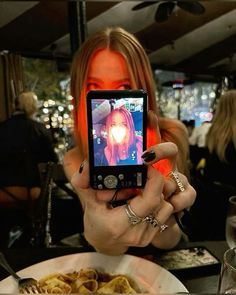 a woman taking a selfie with her cell phone at a table full of food