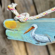 a bird painted on the side of a piece of wood with ropes attached to it