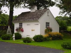 a small white house sitting in the middle of a lush green field