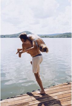 a man doing a handstand on a dock by the water