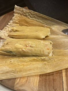 two tamales sitting on top of a wooden cutting board