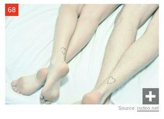 two people laying in bed with their legs crossed and heart tattoos on their ankless