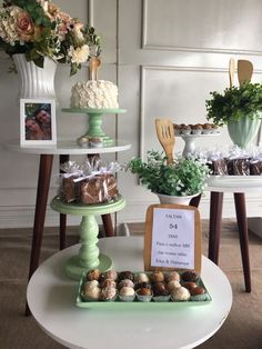 a table topped with cakes and cupcakes covered in frosting next to flowers