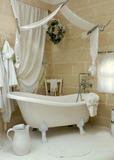 a white bath tub sitting in a bathroom next to a toilet and sink with towels hanging on the wall