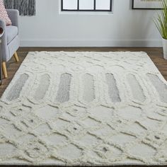 a large white rug in a living room with a chair and potted plant on the floor