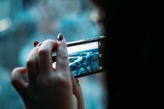 a woman taking a photo with her cell phone in the dark, looking down at an urban area