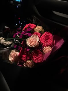 a bouquet of flowers sitting in the center console of a car with its lights on