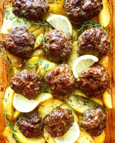 meatballs with potatoes and lemons in a baking dish on a wooden table top