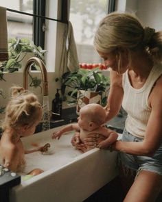 a mother and her two children playing in the bathroom sink