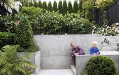 two children sitting on concrete benches in a garden