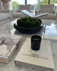 a table with two books and a cup on it next to a bowl of broccoli