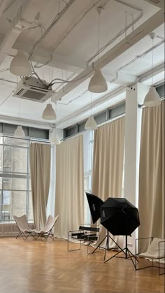 an empty room with chairs, lights and curtains on the windowsills in front of large windows