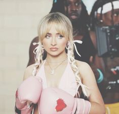 a woman with blonde hair wearing pink boxing gloves