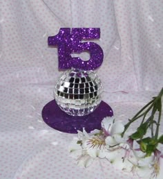 the number five is next to a disco ball and flowers