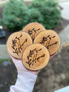 four wooden coasters with the words thank you written on them are held in someone's hand