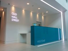 the entrance to an old hall street office with neon signs on the wall and below it is a blue reception counter