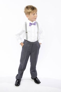 a young boy wearing a bow tie and suspenders standing in front of a white background