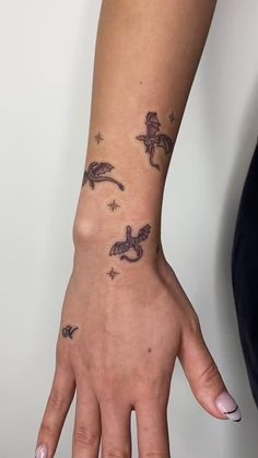 a woman's hand with tattoos on it and stars in the sky behind her