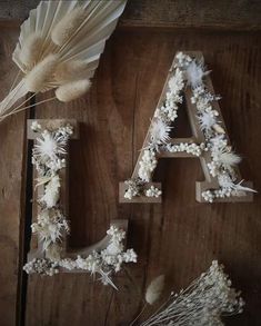 the letters are made out of flowers and feathers on top of a wooden table with a feather fan