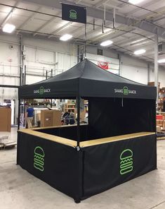 a black tent with green logos on it in a warehouse