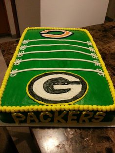 a green and yellow cake with the logo of packers on it, sitting on a counter