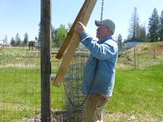 a man holding up a piece of wood near a fence