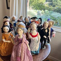 a group of dolls sitting on top of a wooden table in front of a window