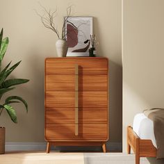 a wooden cabinet sitting next to a bed in a room with a plant on top of it