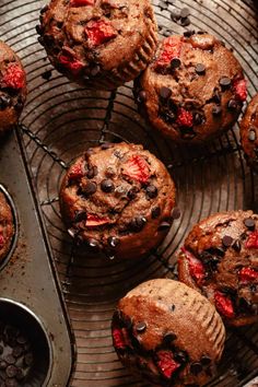 chocolate chip muffins with strawberries and chocolate chips in the middle on a cooling rack