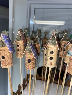 there are many bird houses on sticks in the shape of houses with birds perched on them