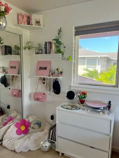 a white dresser sitting next to a window in a room with pink decorations on it