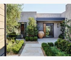 the front entrance to a modern home with plants and trees in pots on either side