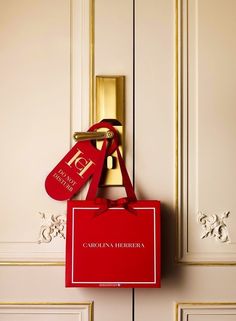 a red bag hanging from the side of a door with a name tag on it