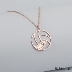 a volleyball necklace with the number 13 on it's front and back, hanging from a gold plated chain