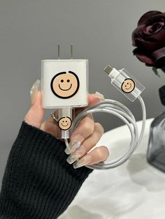 a woman is holding an electric outlet with smiley faces on it and plugged in