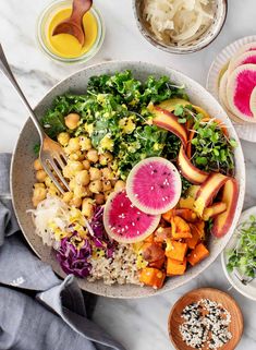 a bowl filled with different types of vegetables and fruit on top of a white table