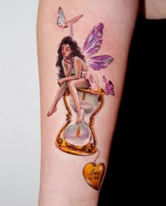 a woman sitting on top of an hourglass with butterflies flying around her and a heart hanging from it